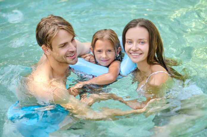 cute-girl-her-parents-spending-time-swimming-pool_1300x865